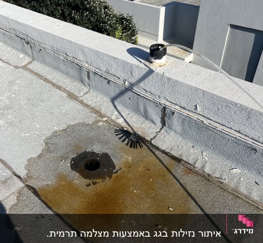 נזילת מים על גג עם כתם רטוב סביב פתח ניקוז
